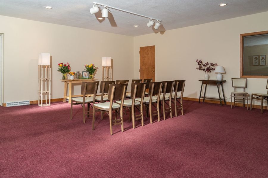 A row of chairs are lined up in a room with a red carpet.