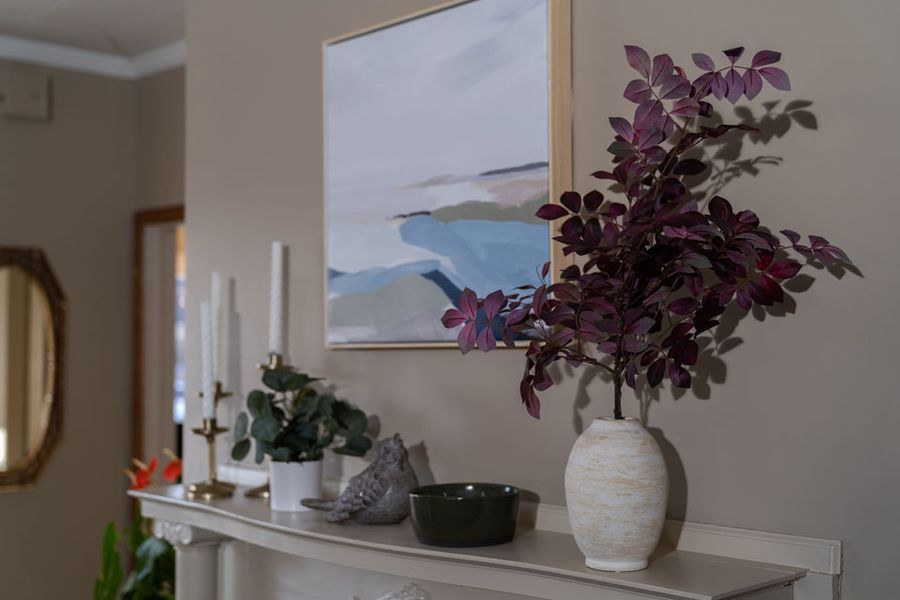 A vase of flowers is sitting on a mantle in a living room.