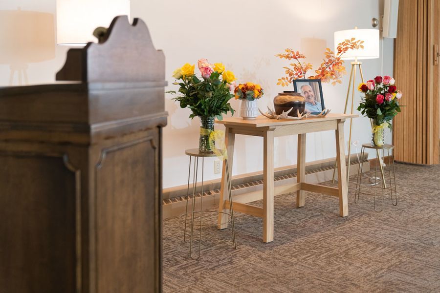 A wooden table with flowers and a picture on it in a room.