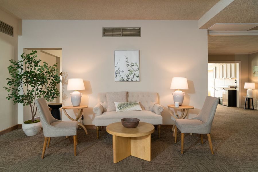 A living room with a couch , chairs , tables and lamps.