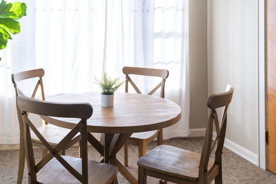 A wooden table and chairs in a room next to a window.