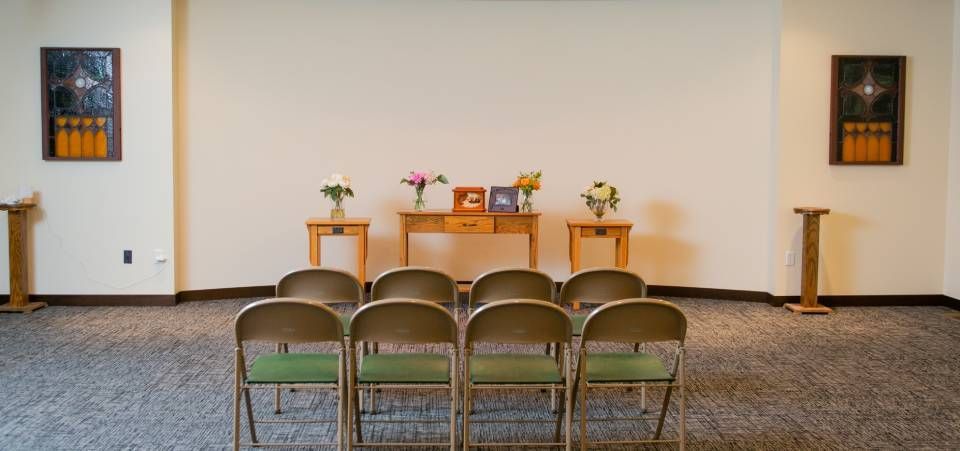 A room with a row of chairs and a table with flowers on it.