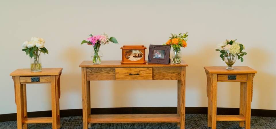 A wooden table with flowers and pictures on it in a room.