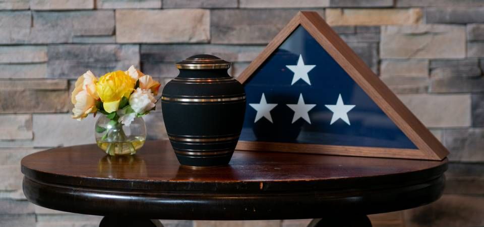 A black urn is sitting on a table next to an american flag.