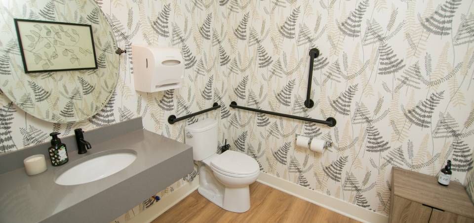 A bathroom with a toilet , sink and mirror.