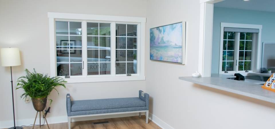 A living room with a bench , lamp , and window.