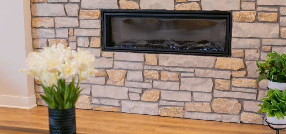 A fireplace with a brick wall and a vase of flowers in front of it.