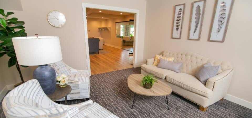 A living room with a couch , chair , table and lamp.