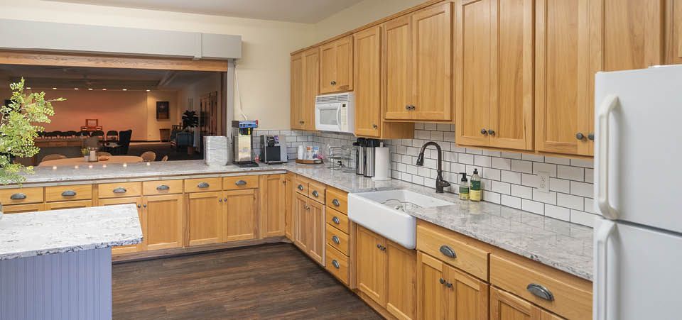 A kitchen with wooden cabinets , granite counter tops , a refrigerator and a sink.