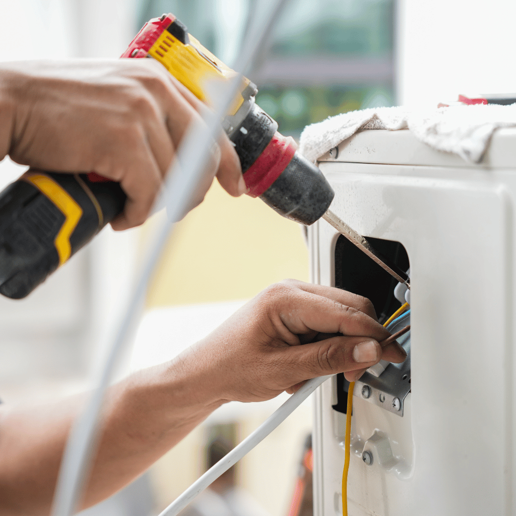 Person using a drill to install wires into an appliance.