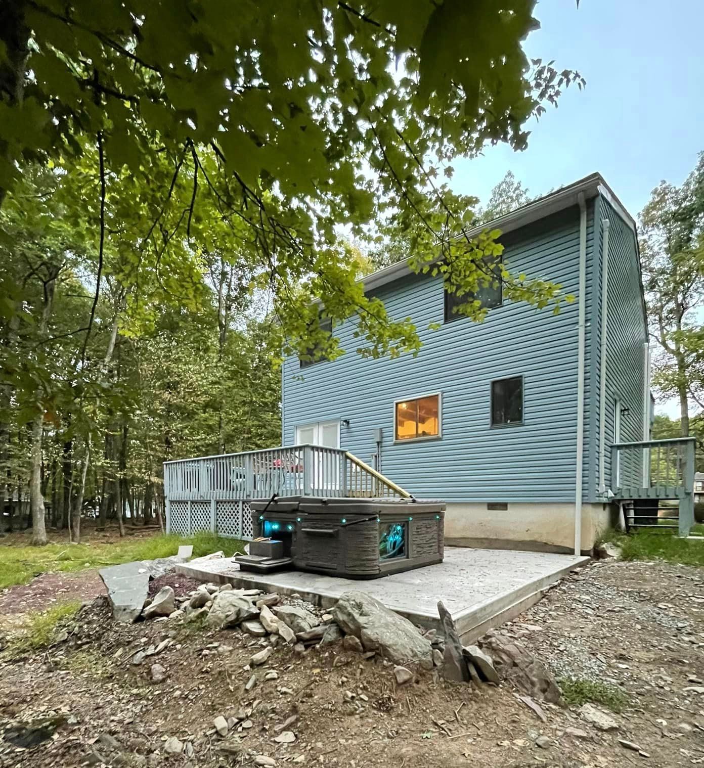 A house with a hot tub on the patio in front of it.