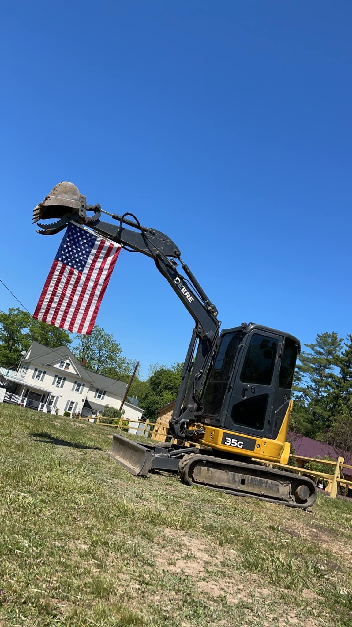 A  Tailored Excavation bulldozer is sitting in a field with an american flag in the background.