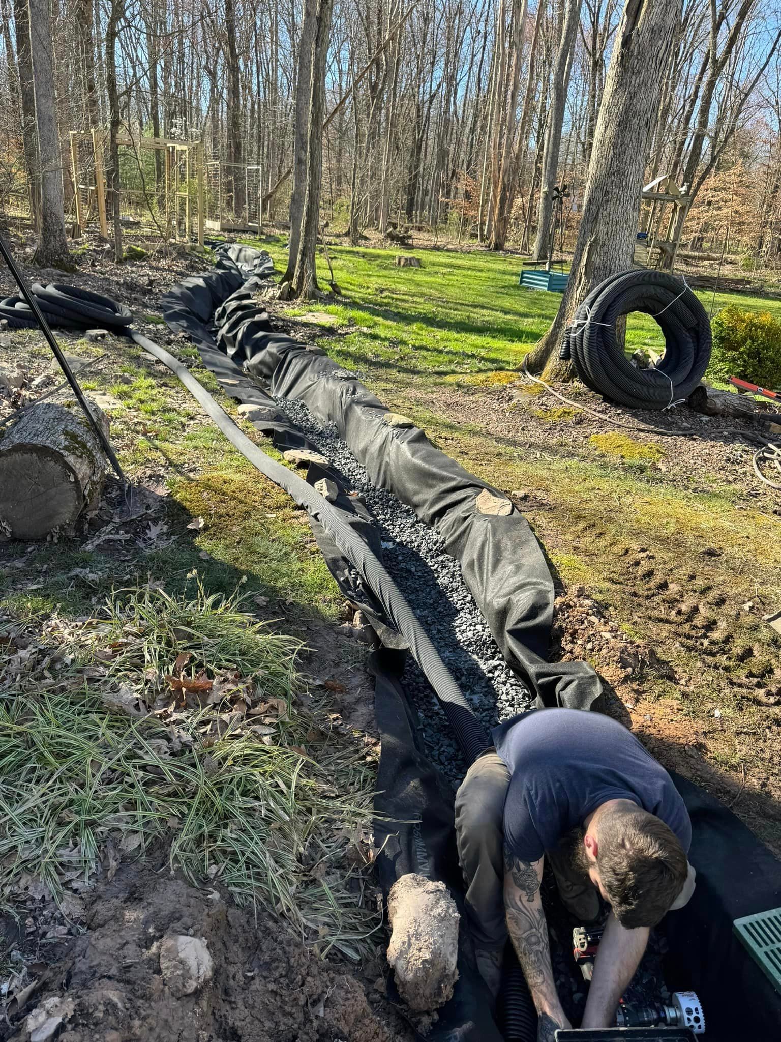 Tailored Excavation is working on a drainage system on a home in the woods.