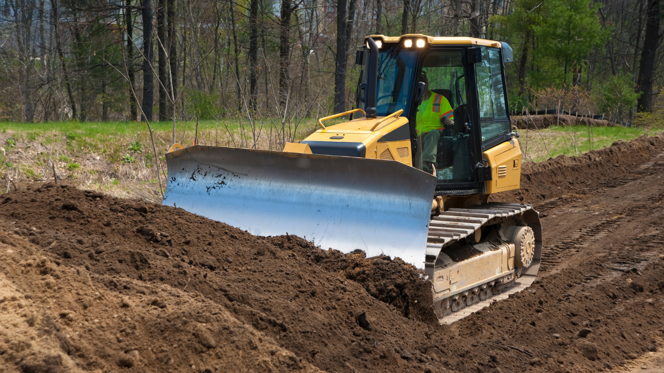 A couple of excavators are working on a dirt field.