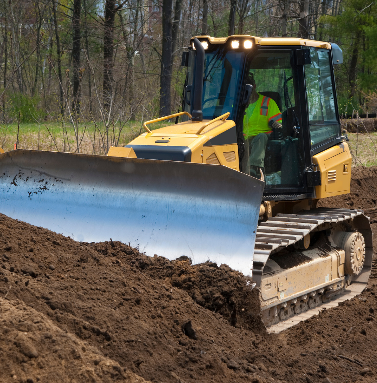 A large orange excavator is moving dirt in a field