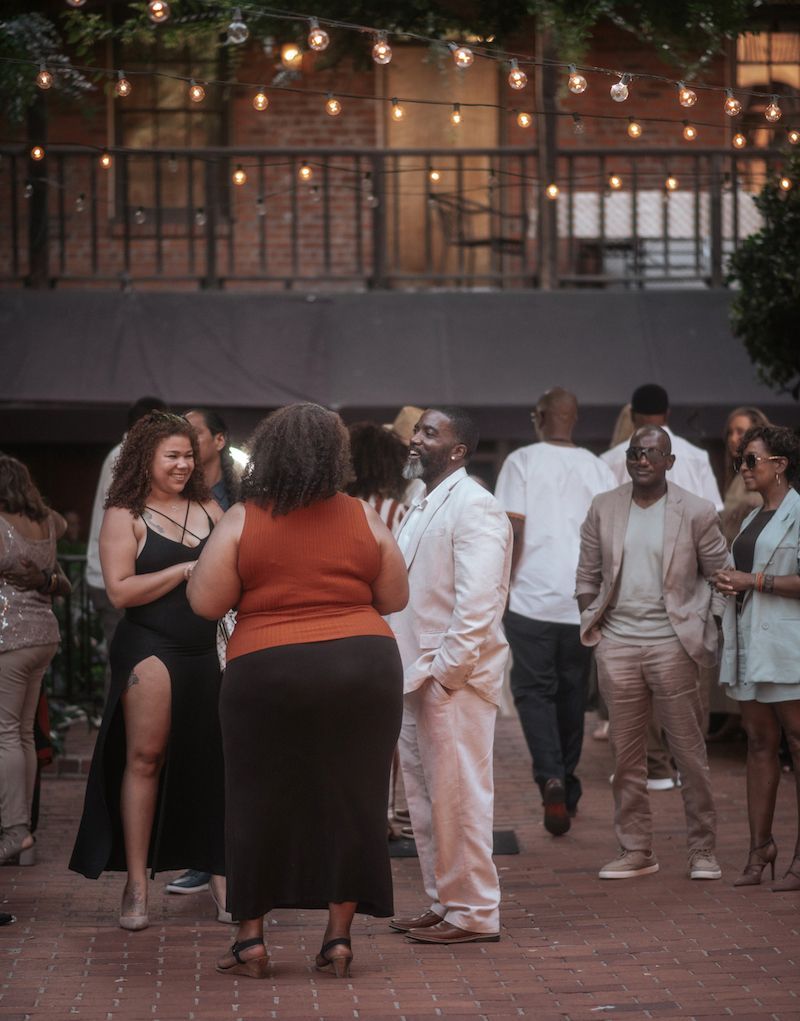 A group of people are standing on a sidewalk talking to each other.