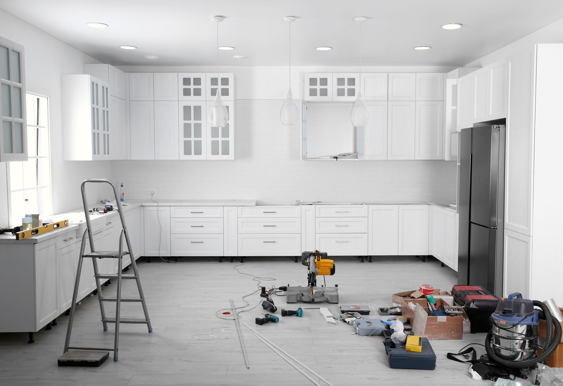 a kitchen is being remodeled with white cabinets and a ladder .