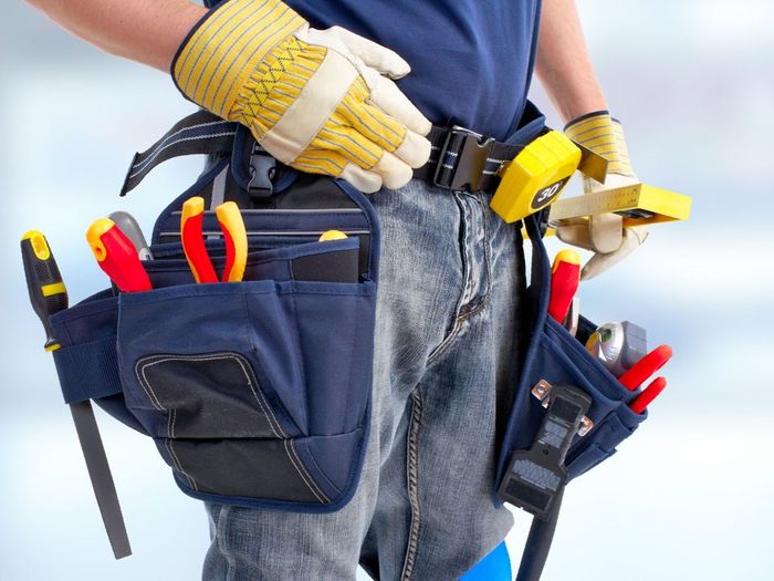 a man wearing gloves and a tool belt with tools in it