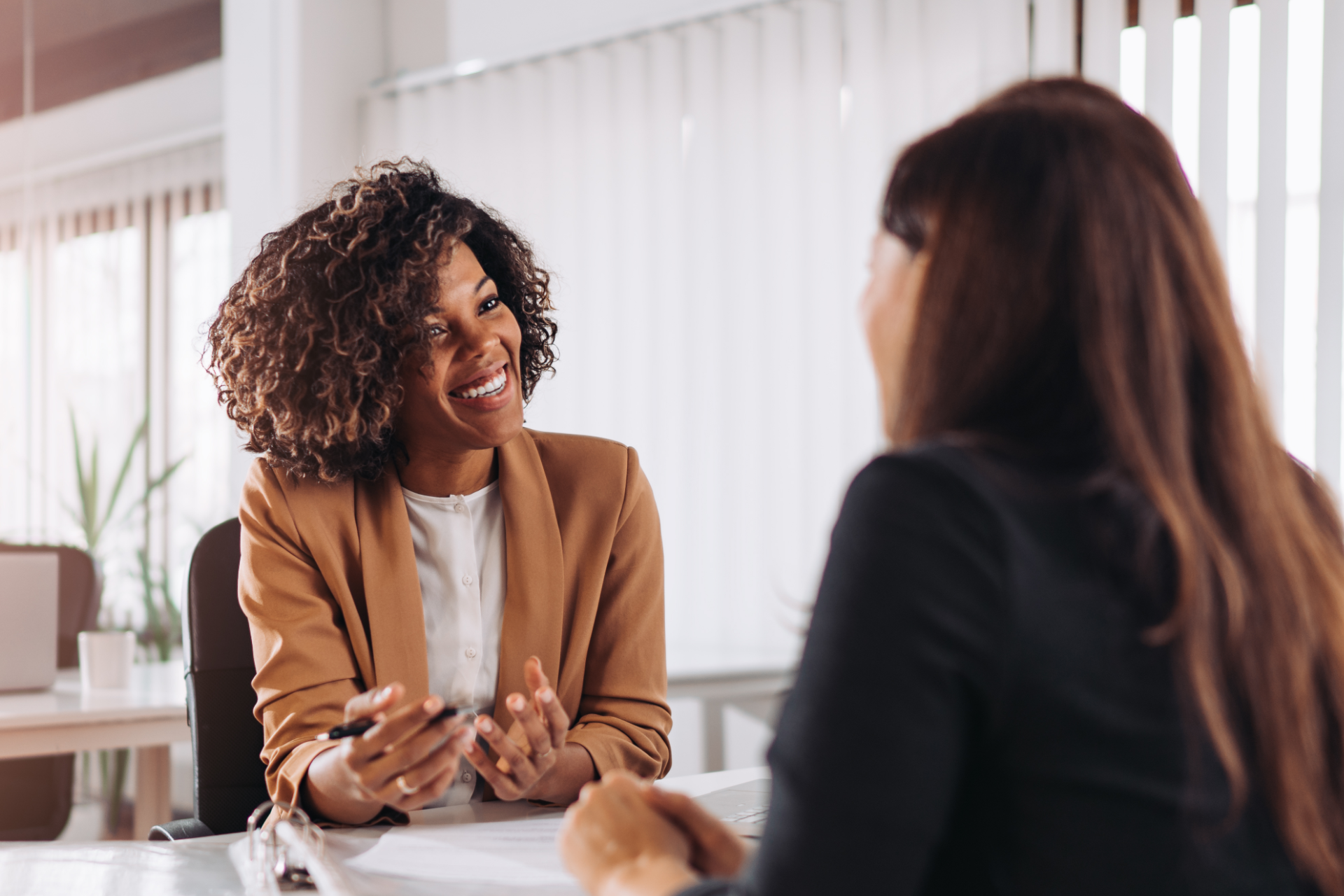 A man is sitting at a table with his arms crossed and smiling.