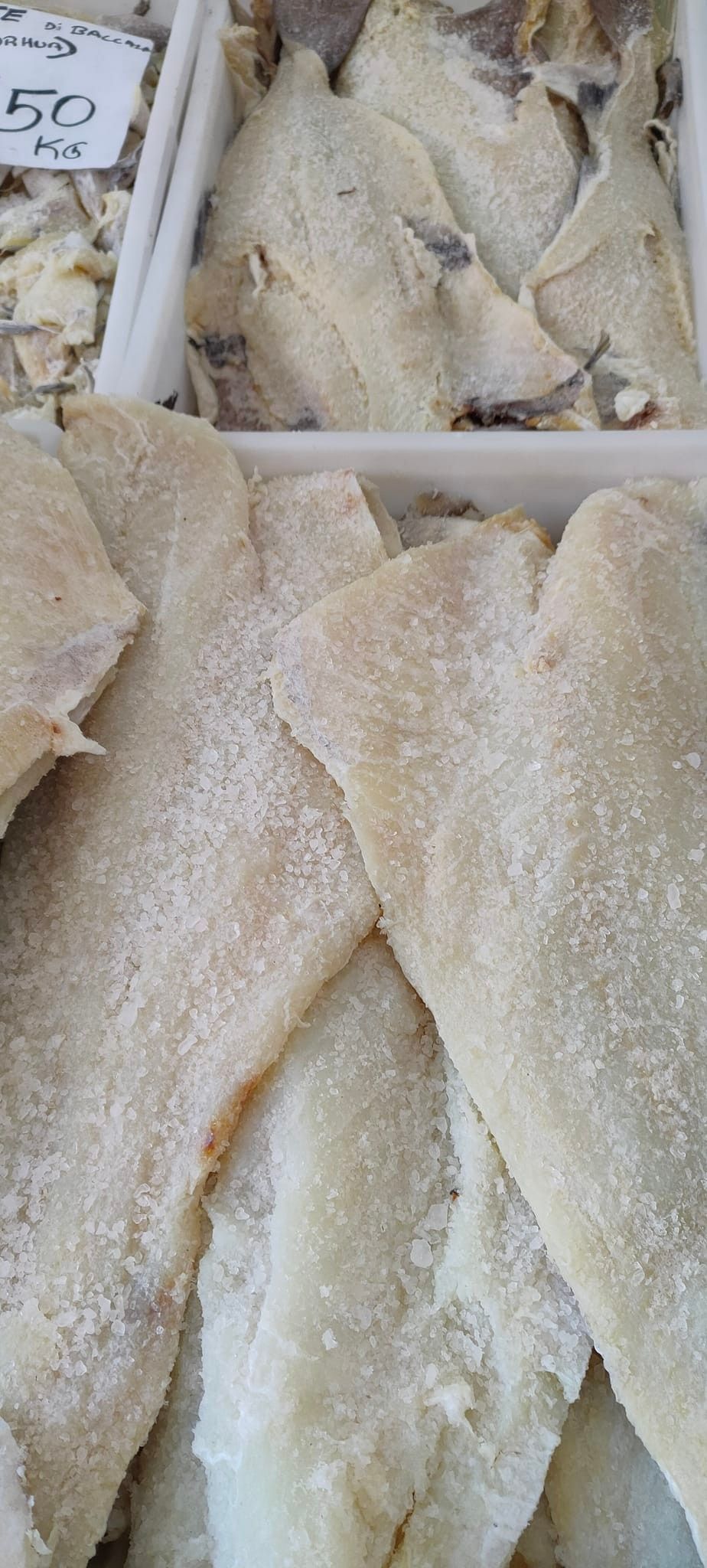 Filetti di merluzzo salato in contenitori di plastica bianca.