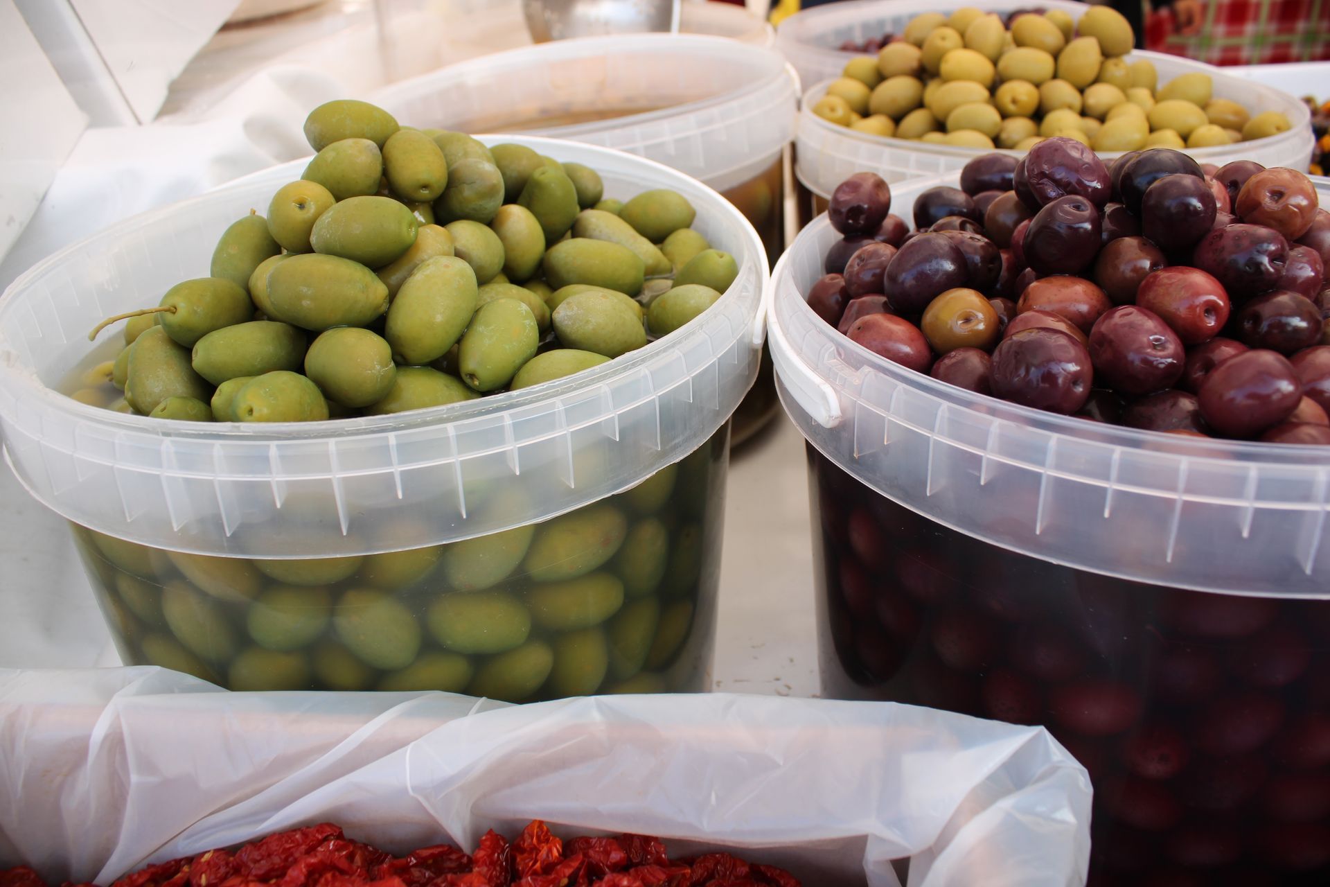 Secchi di olive verdi, marroni e nere su una bancarella del mercato.