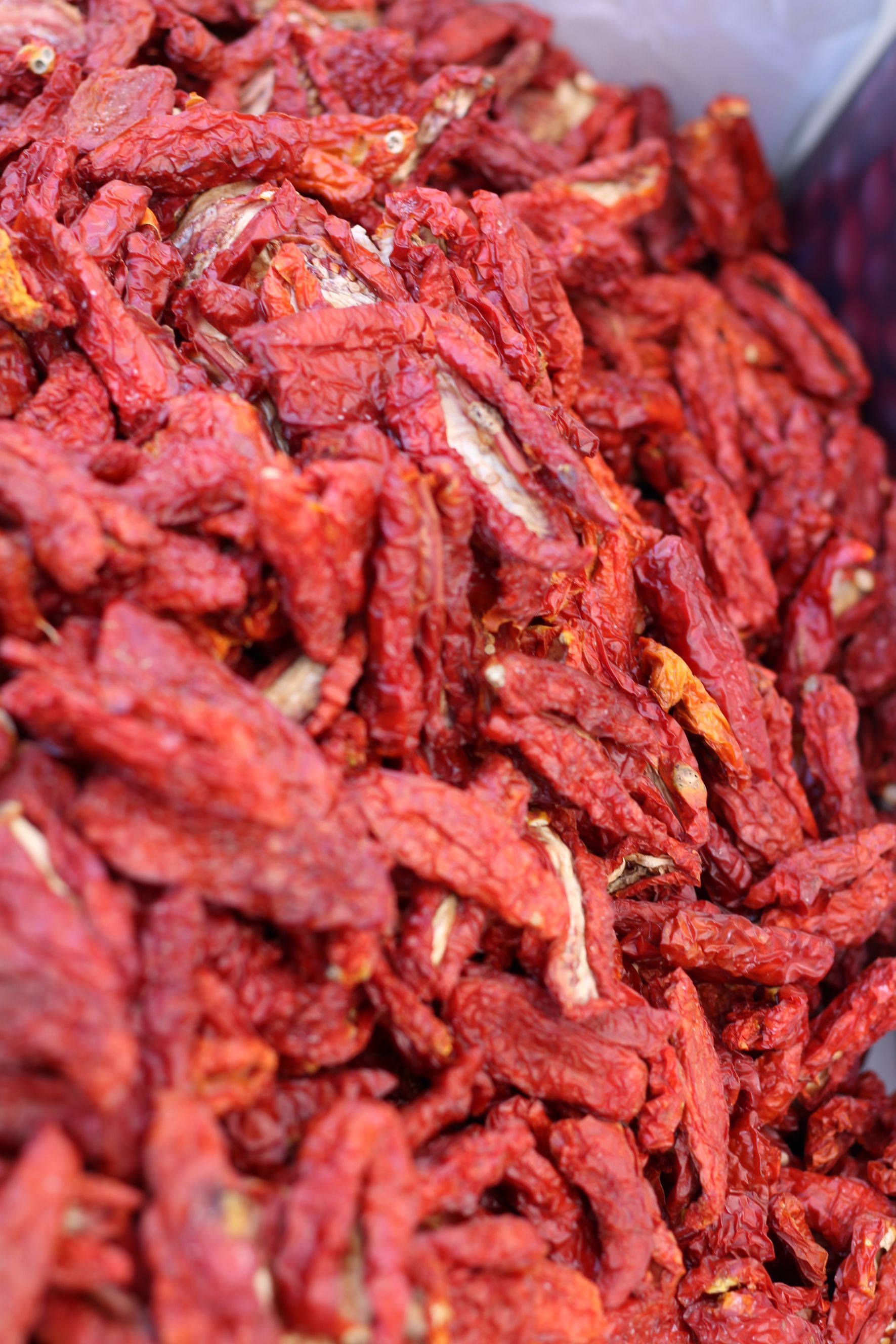 Pomodori rossi secchi essiccati al sole; primo piano che rivela la superficie strutturata e le forme varie.