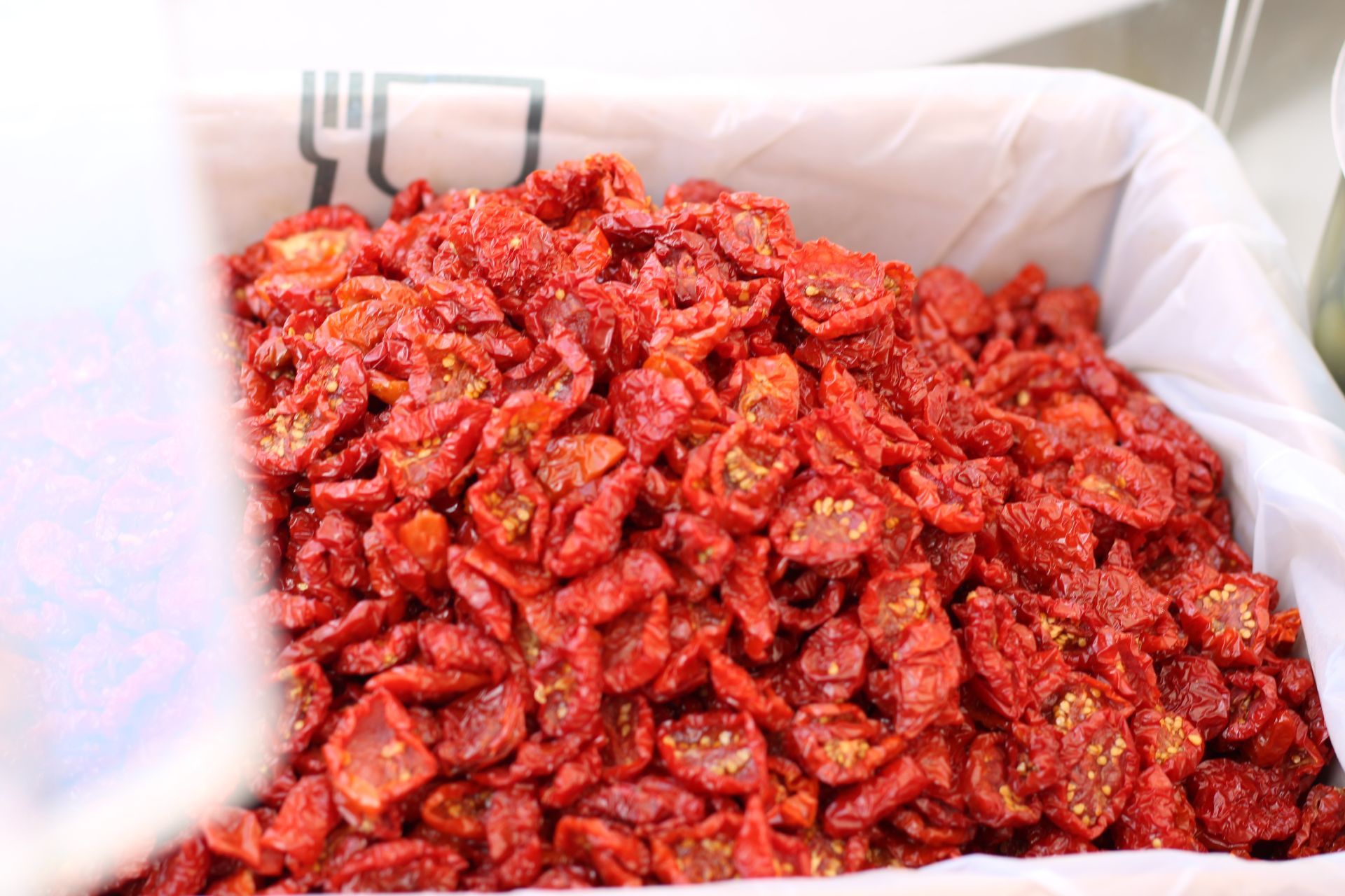 Mucchio di pomodori rossi secchi in un contenitore bianco, probabilmente al mercato.