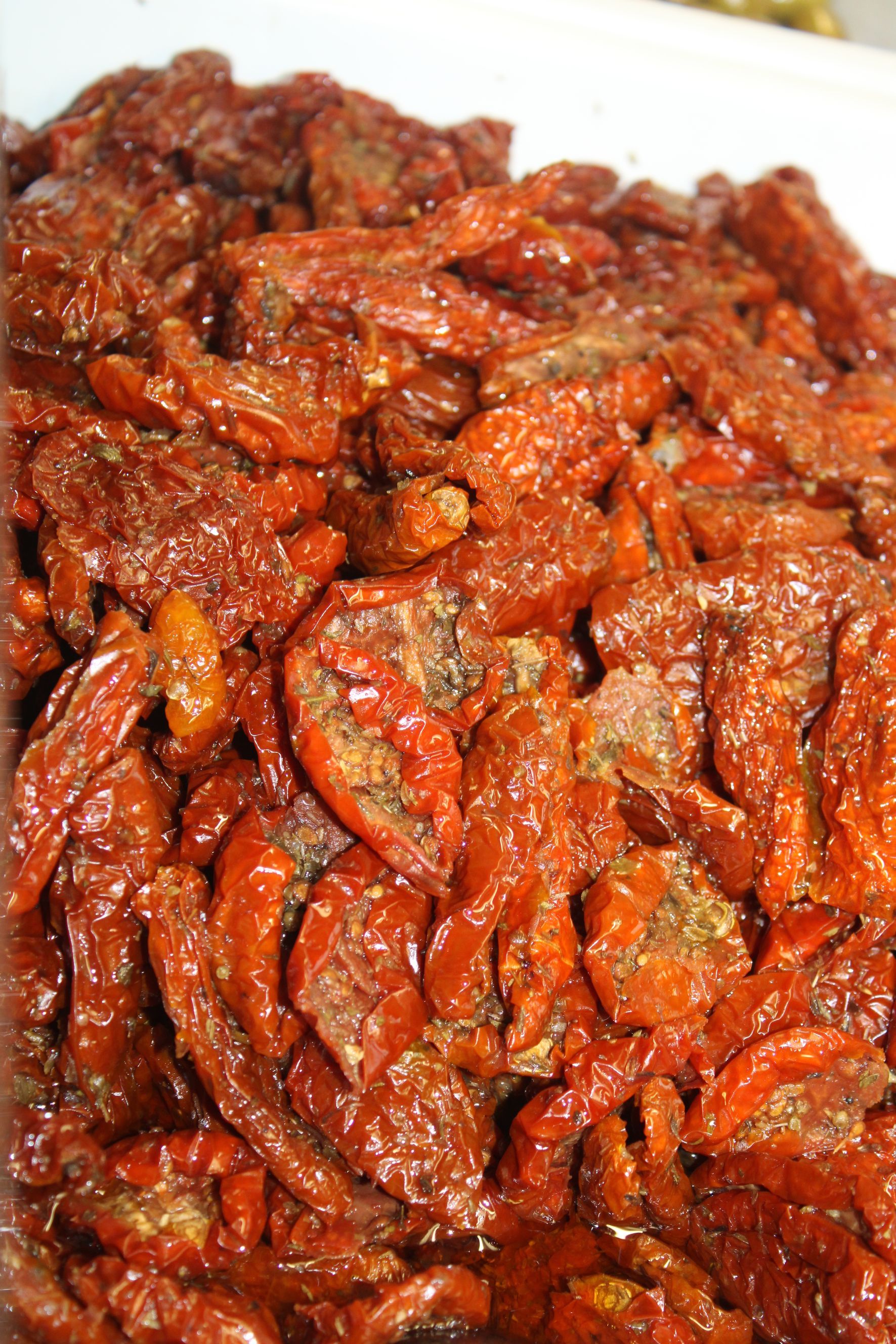 Pomodori secchi al sole in un contenitore, di colore bruno-rossastro, oleosi.