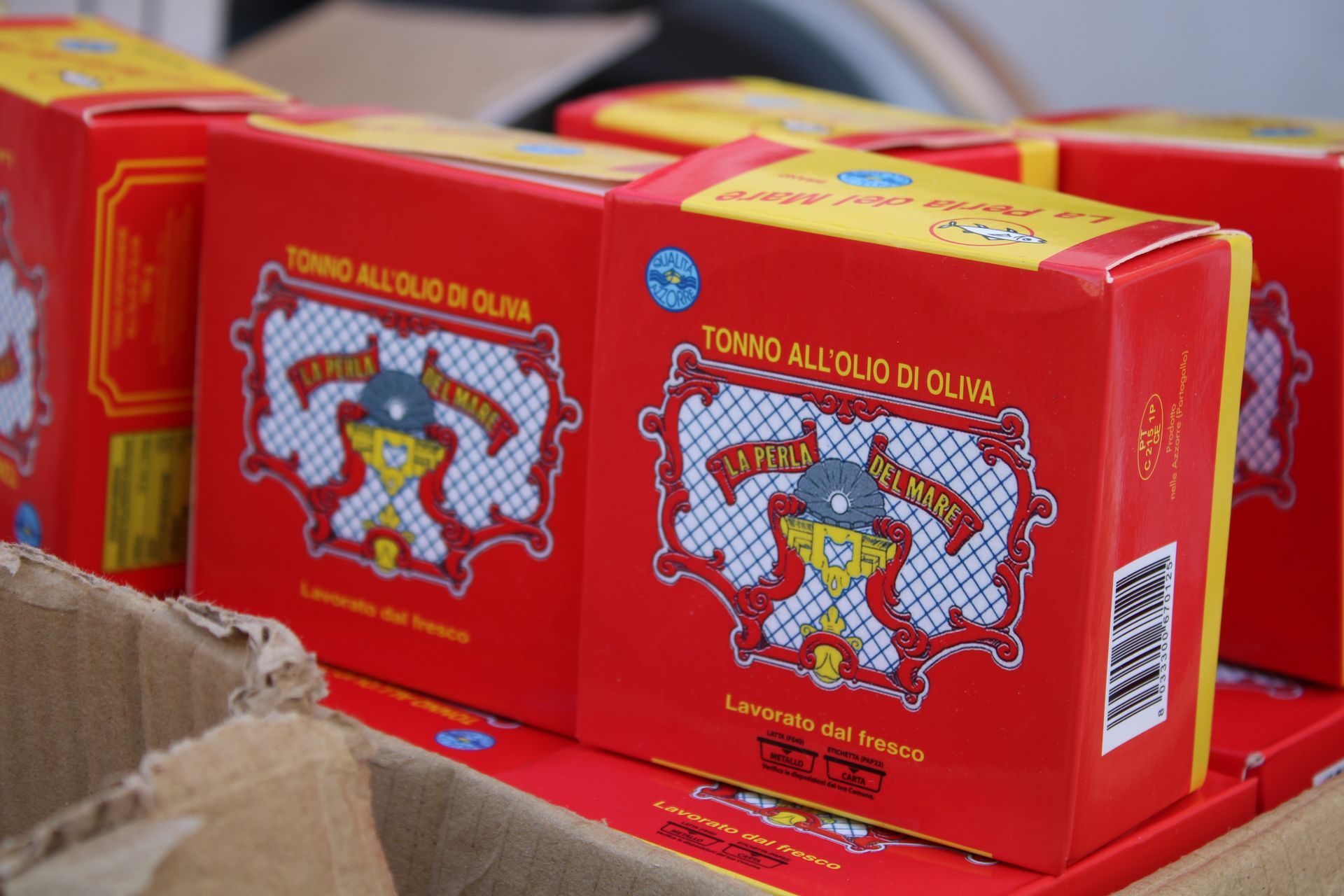 Scatole rosse di tonno all'olio di oliva, impilate in una scatola di cartone.