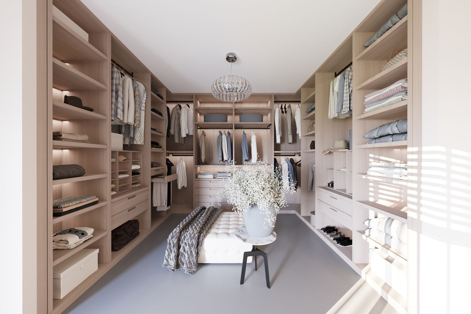 Walk-in closet with beige shelving, clothes, and a bench. A chandelier hangs from the ceiling.