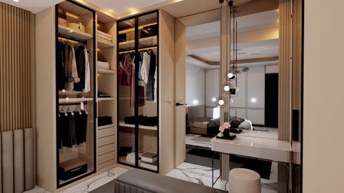 Walk-in closet with beige and black accents, leading to a bedroom with a vanity and bed.
