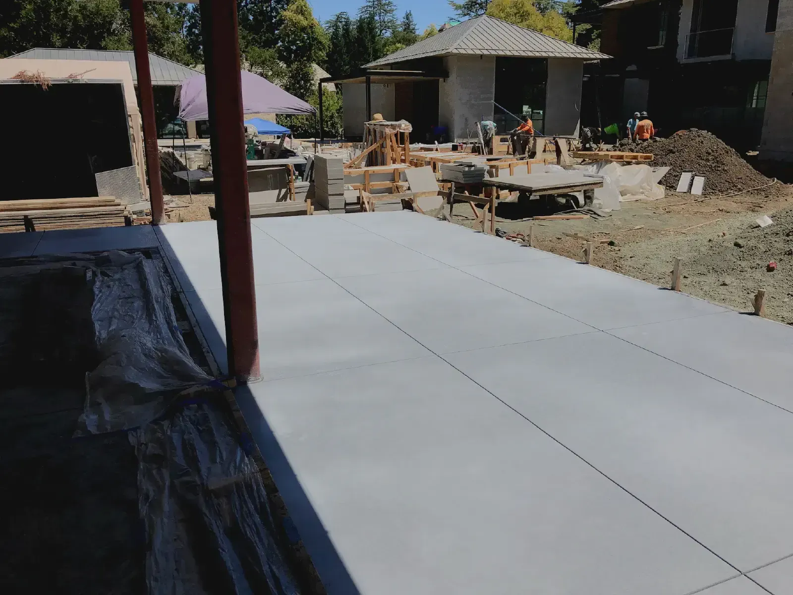 Concrete slab being poured at a construction site, with buildings and equipment visible in the background.