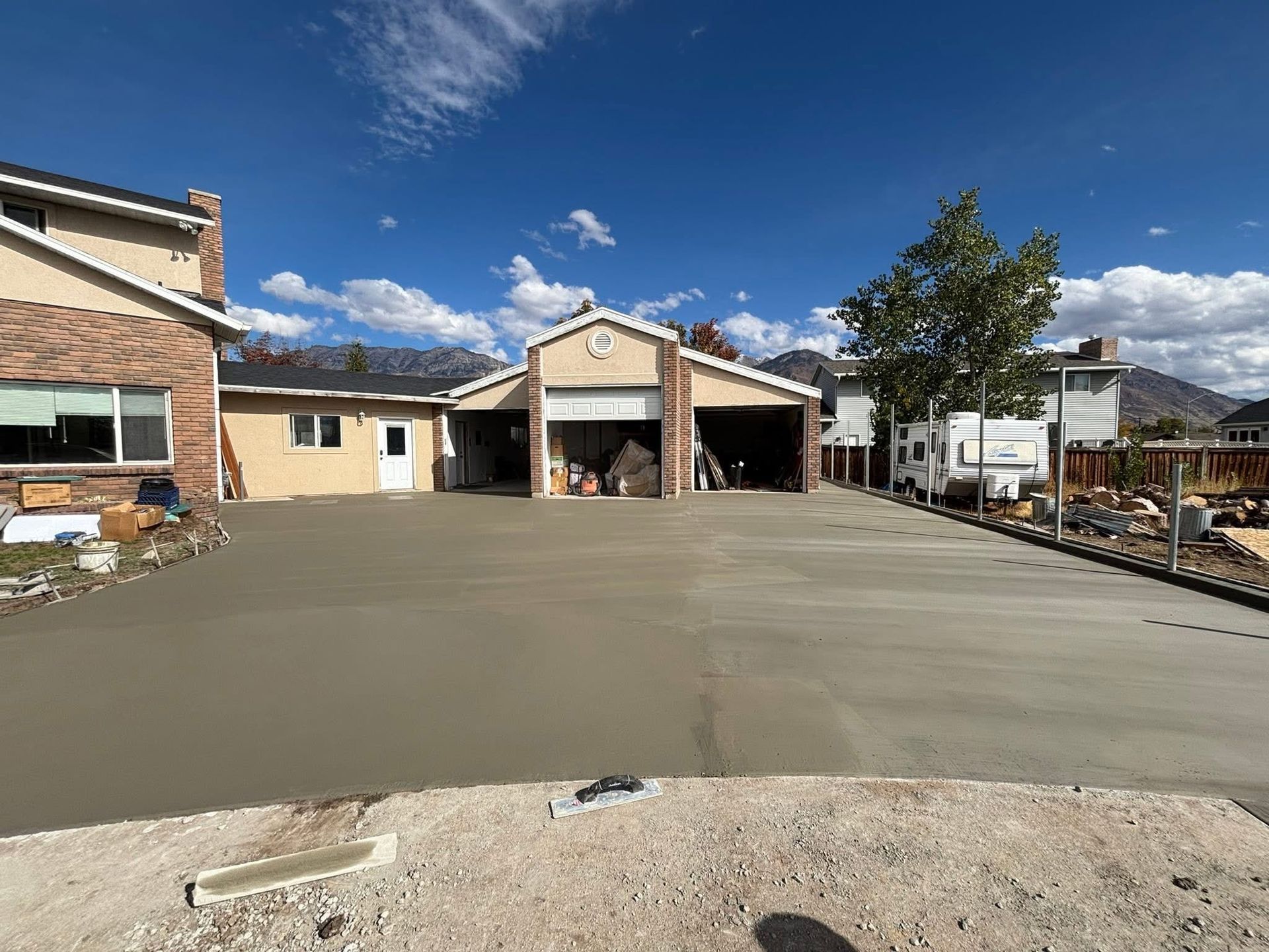 Newly poured concrete driveway in front of a house and garage on a sunny day.