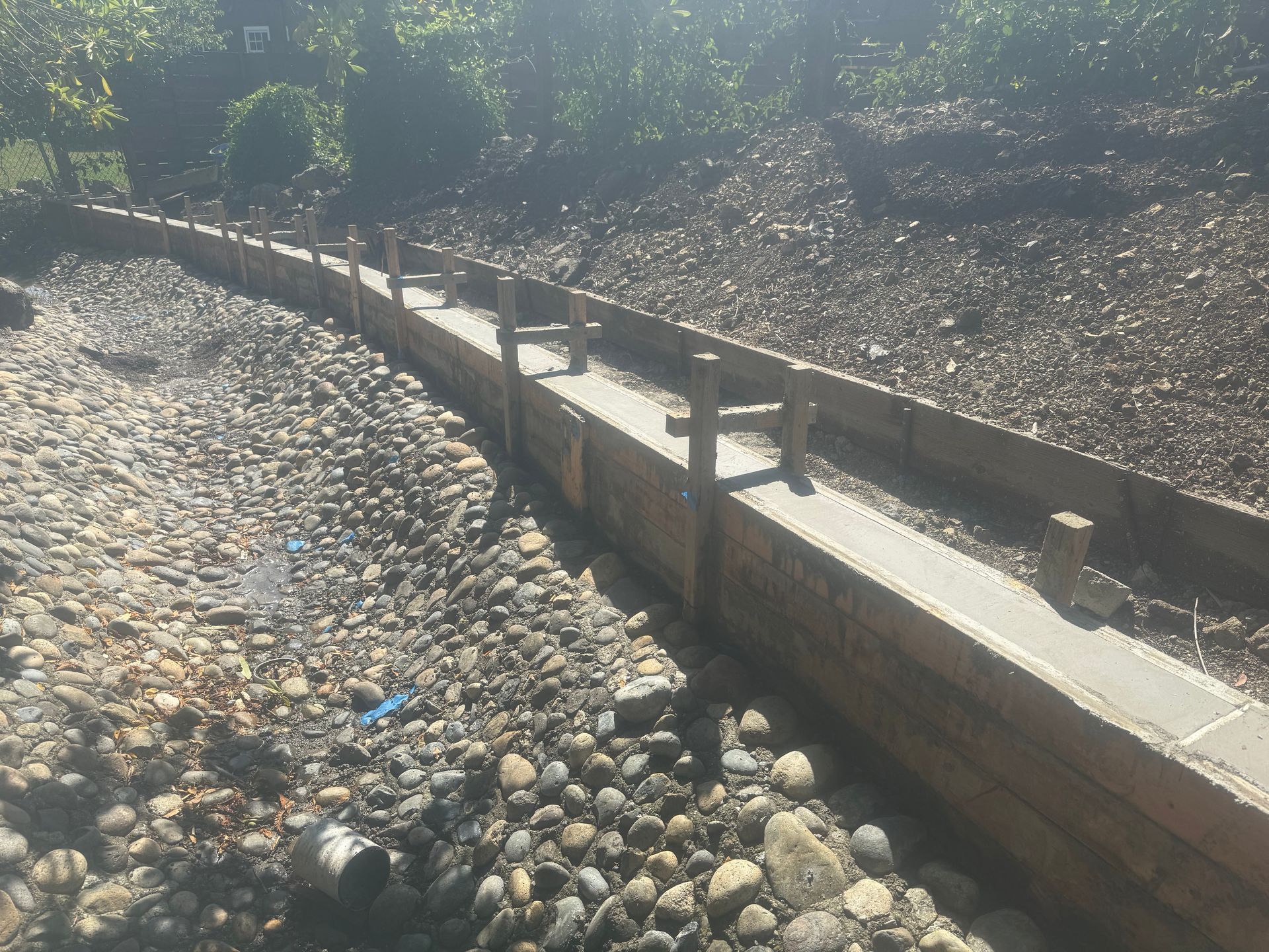 Wooden retaining wall along a gravel riverbed.