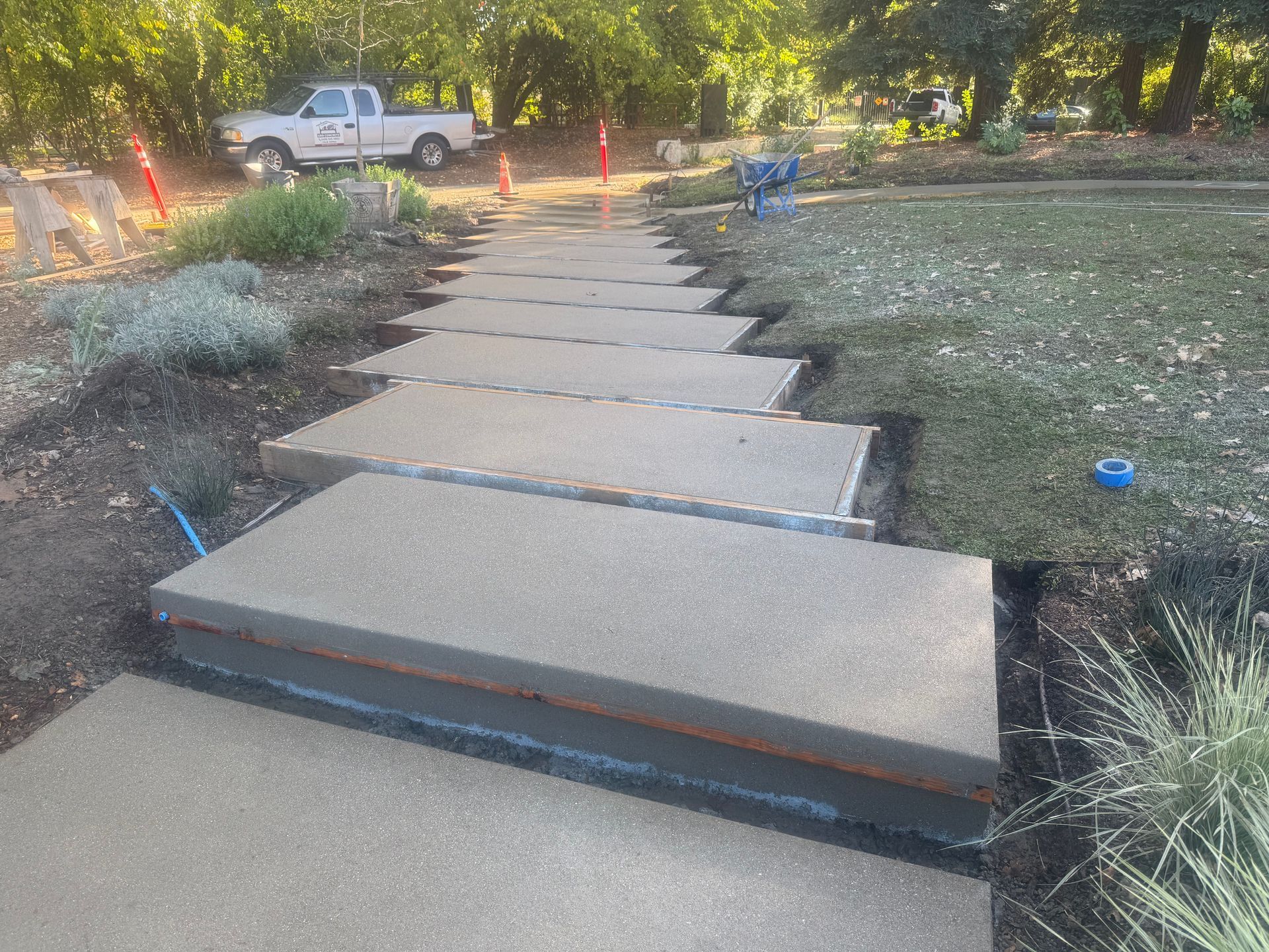 Newly poured concrete walkway with rectangular steps being constructed outdoors.