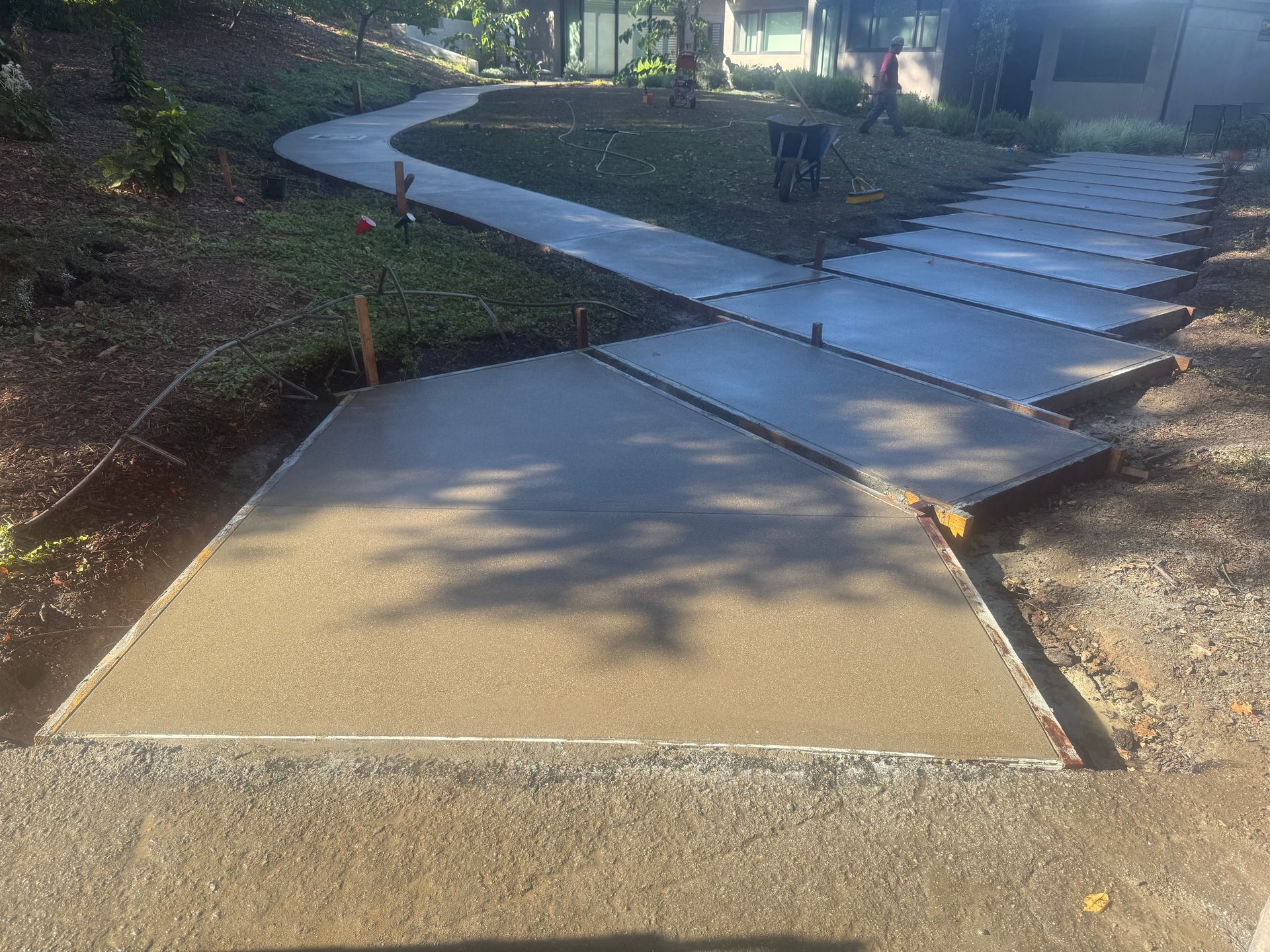 Newly poured concrete pathways and patios in a residential setting; angled design.