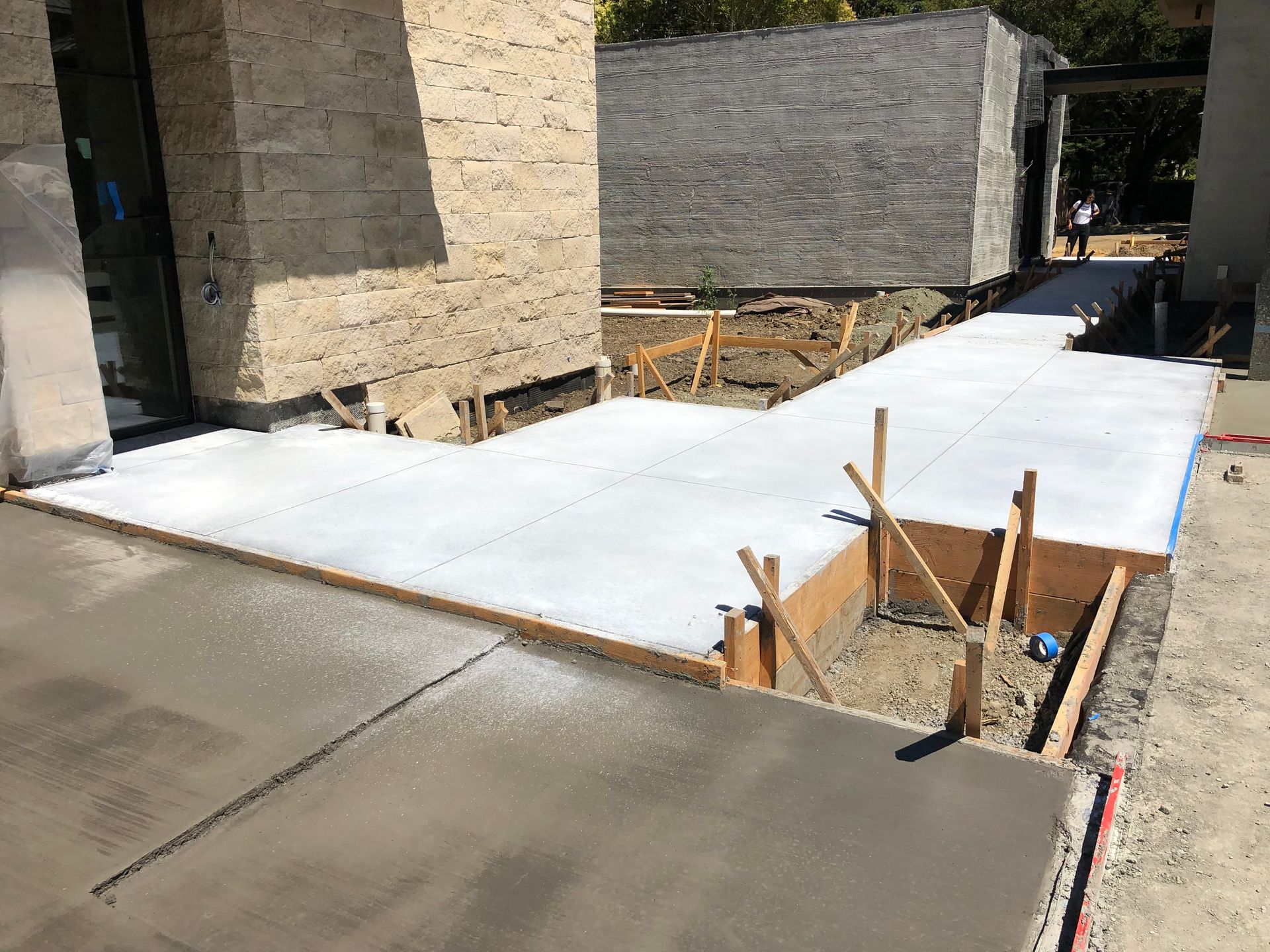Newly poured concrete sidewalk with wooden forms in a construction site.