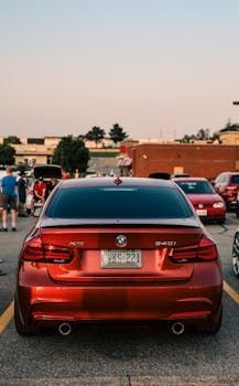Red BMW 340i sedan parked in a lot, with two exhaust pipes, license plate visible.