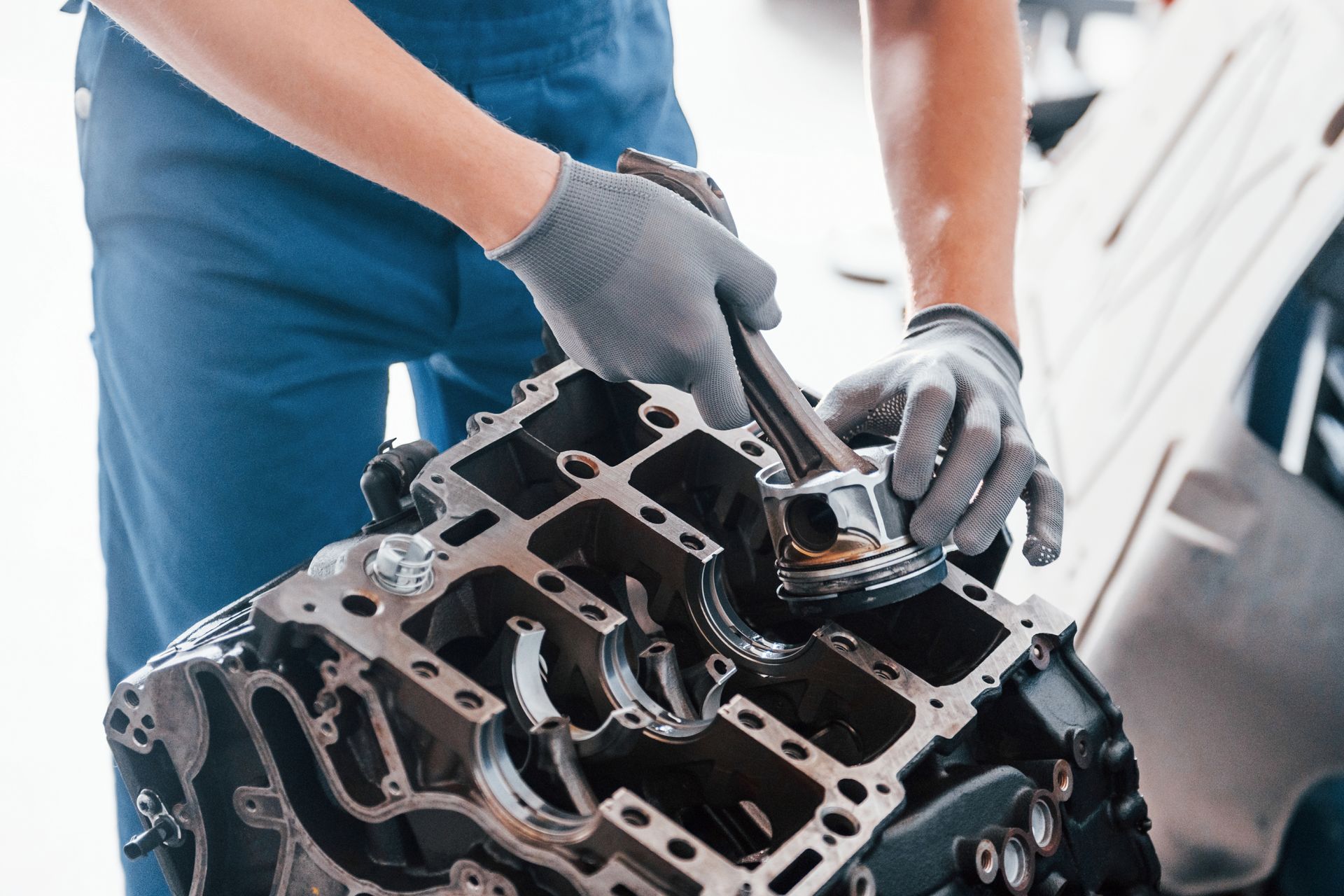 Mechanic wearing gloves inspecting an engine block in a car repair shop