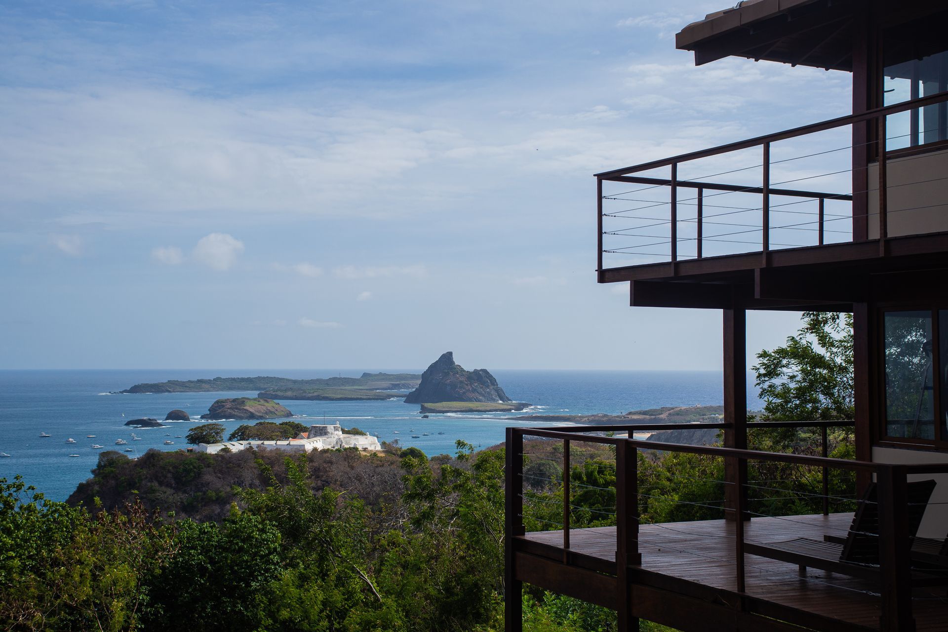 Uma casa com varanda com vista para o oceano e as ilhas.