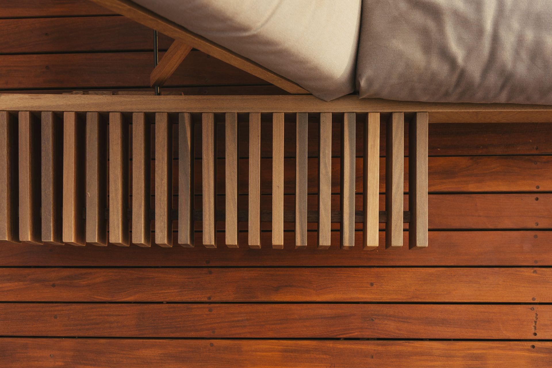 Um banco de madeira está em cima de um deck de madeira ao lado de um sofá.