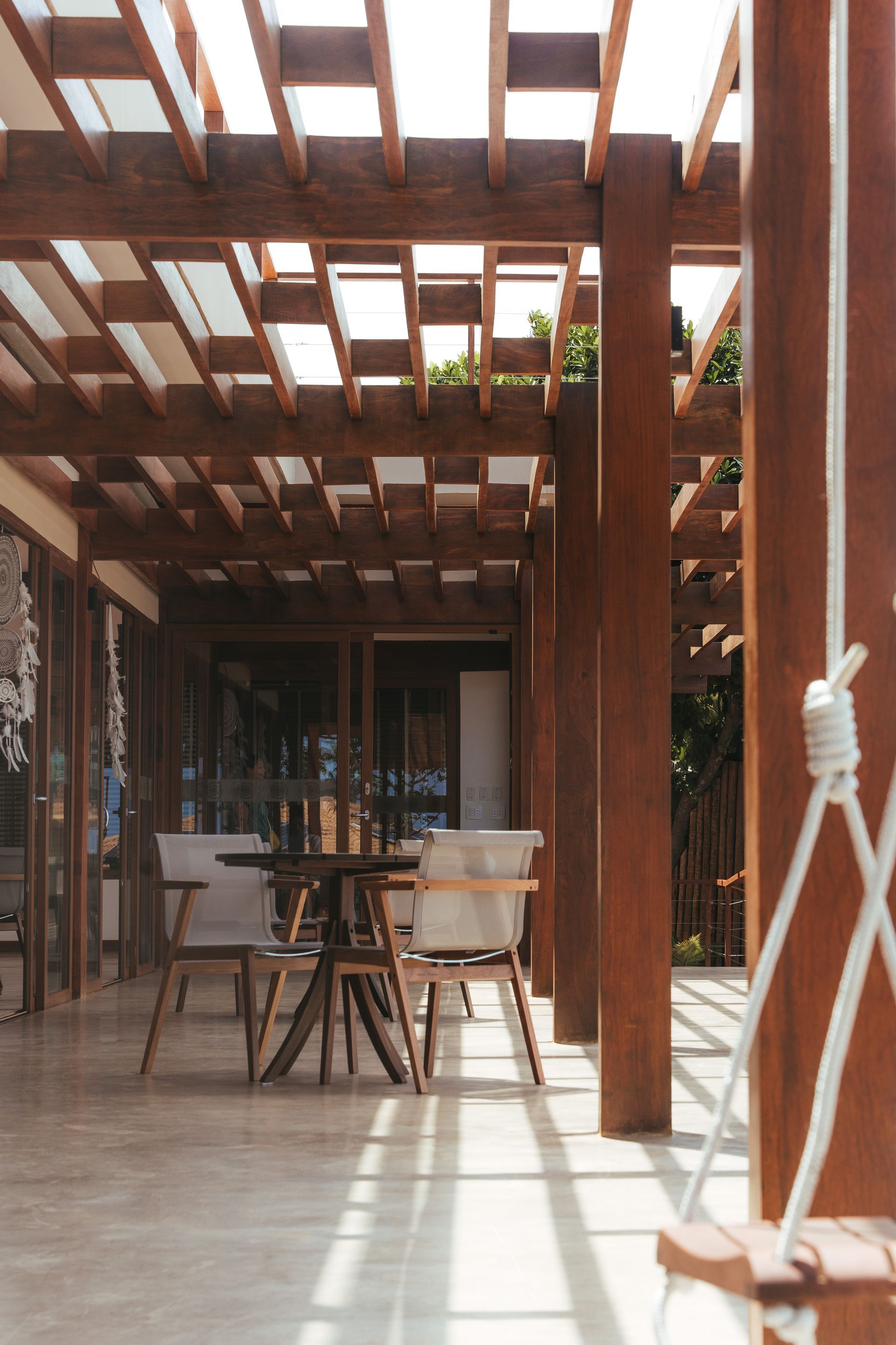 Uma pérgola de madeira com uma mesa e cadeiras embaixo dela