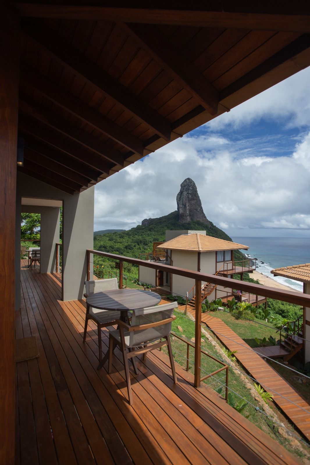 Uma varanda com mesa e cadeiras com vista para o oceano e uma montanha.