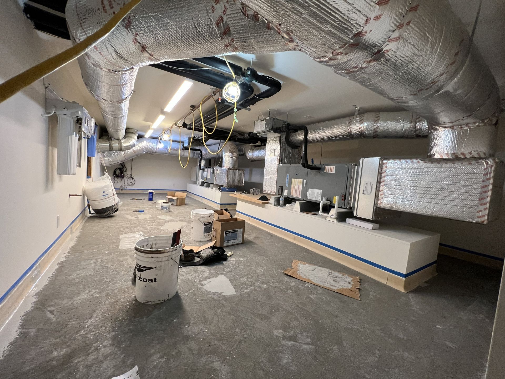 Two men reviewing blueprints, one pointing at a screen, other wearing a hard hat and safety vest.