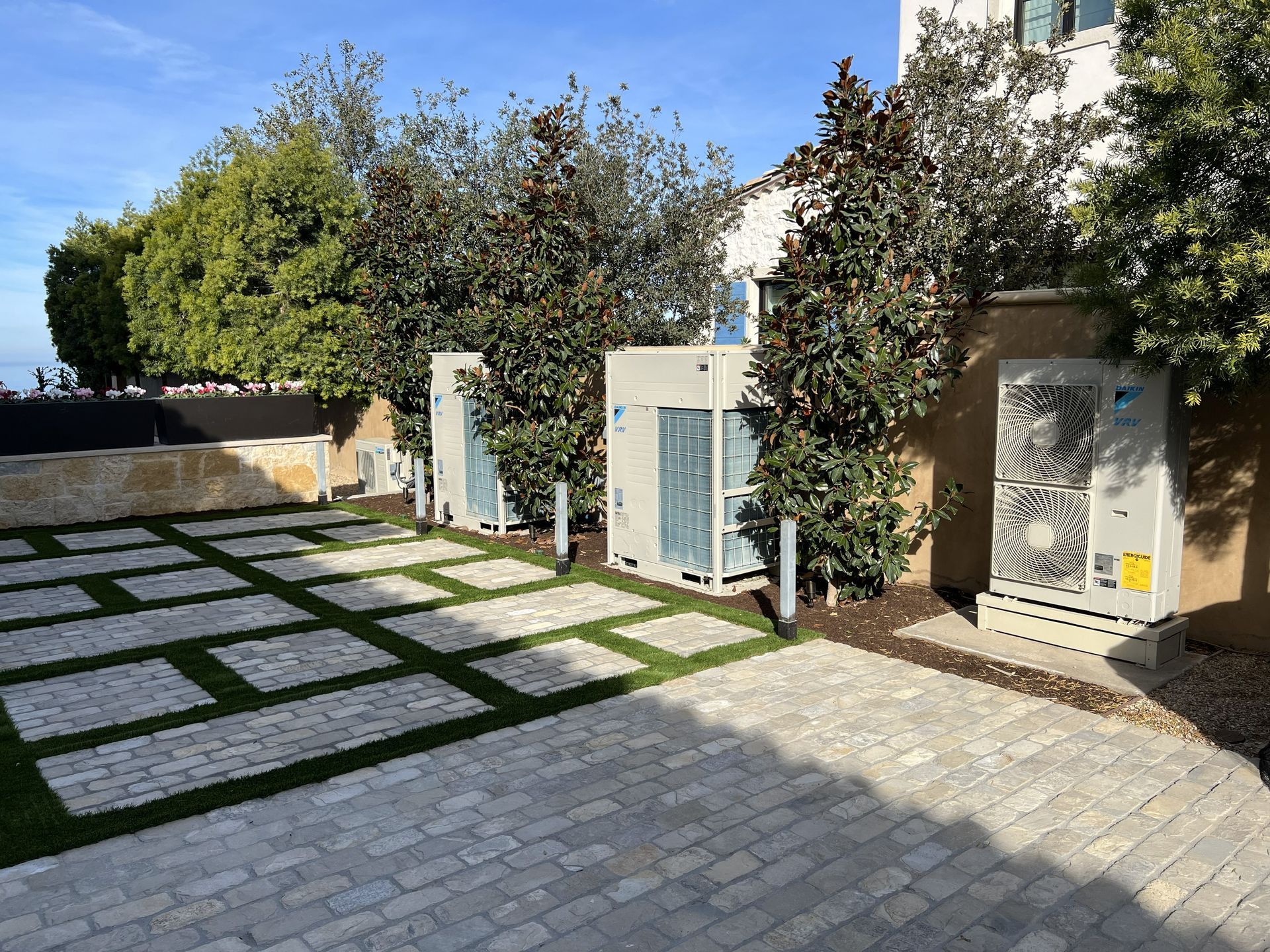 Three construction workers in hard hats and vests review blueprints in a large interior space.