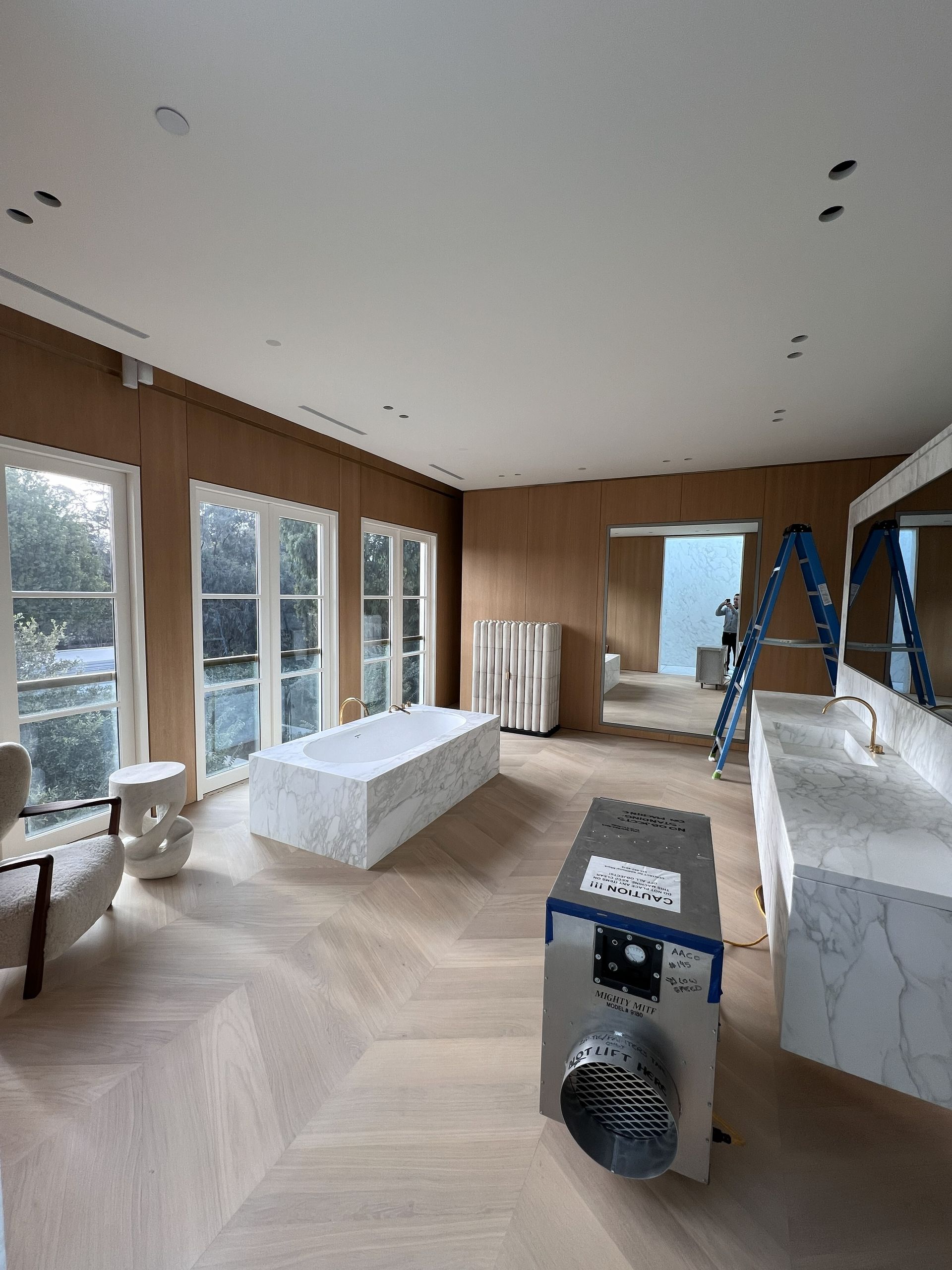 Narrow urban alleyway; wall with air conditioning units, metal door, beer kegs, and plumbing.