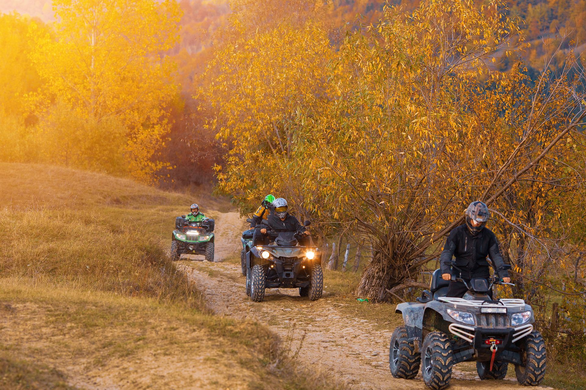 a group of people are riding atvs down a dirt road