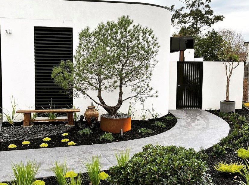 A white house with a tree in front of it and a walkway leading to it.