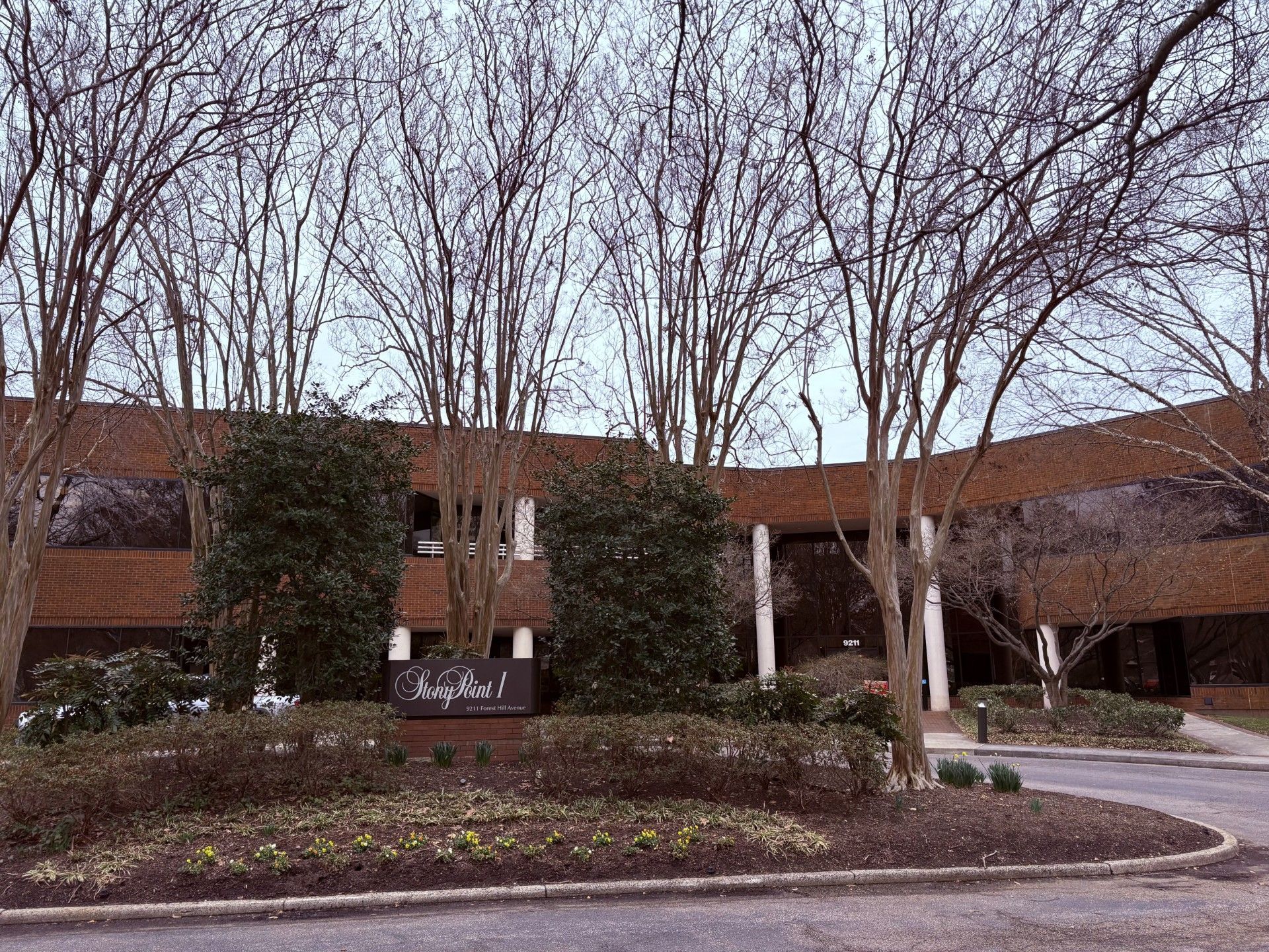 Office building with brick exterior, white columns, glass windows, and a blue sky.