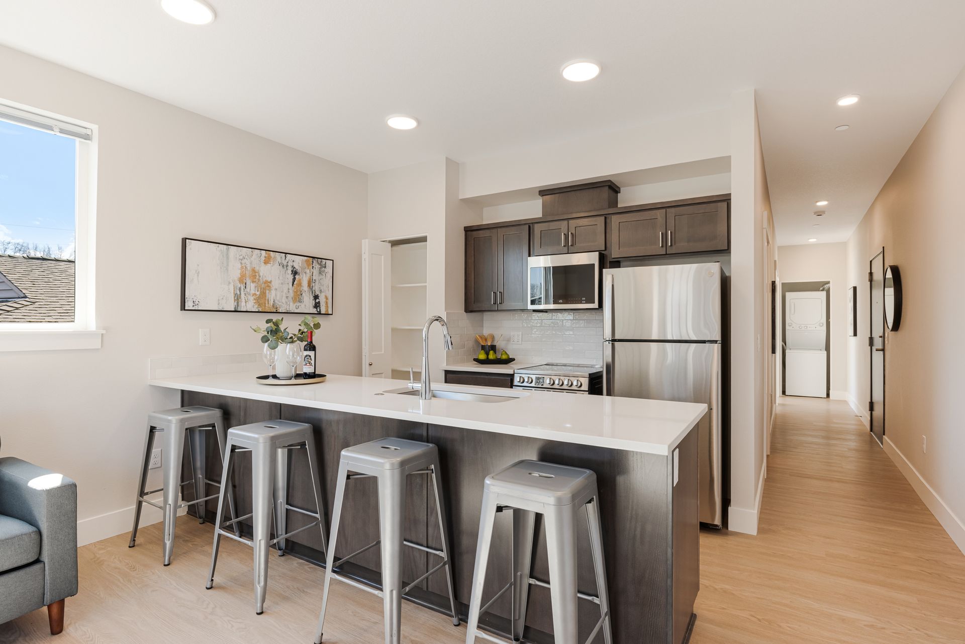A kitchen with stainless steel appliances and a large island with stools.